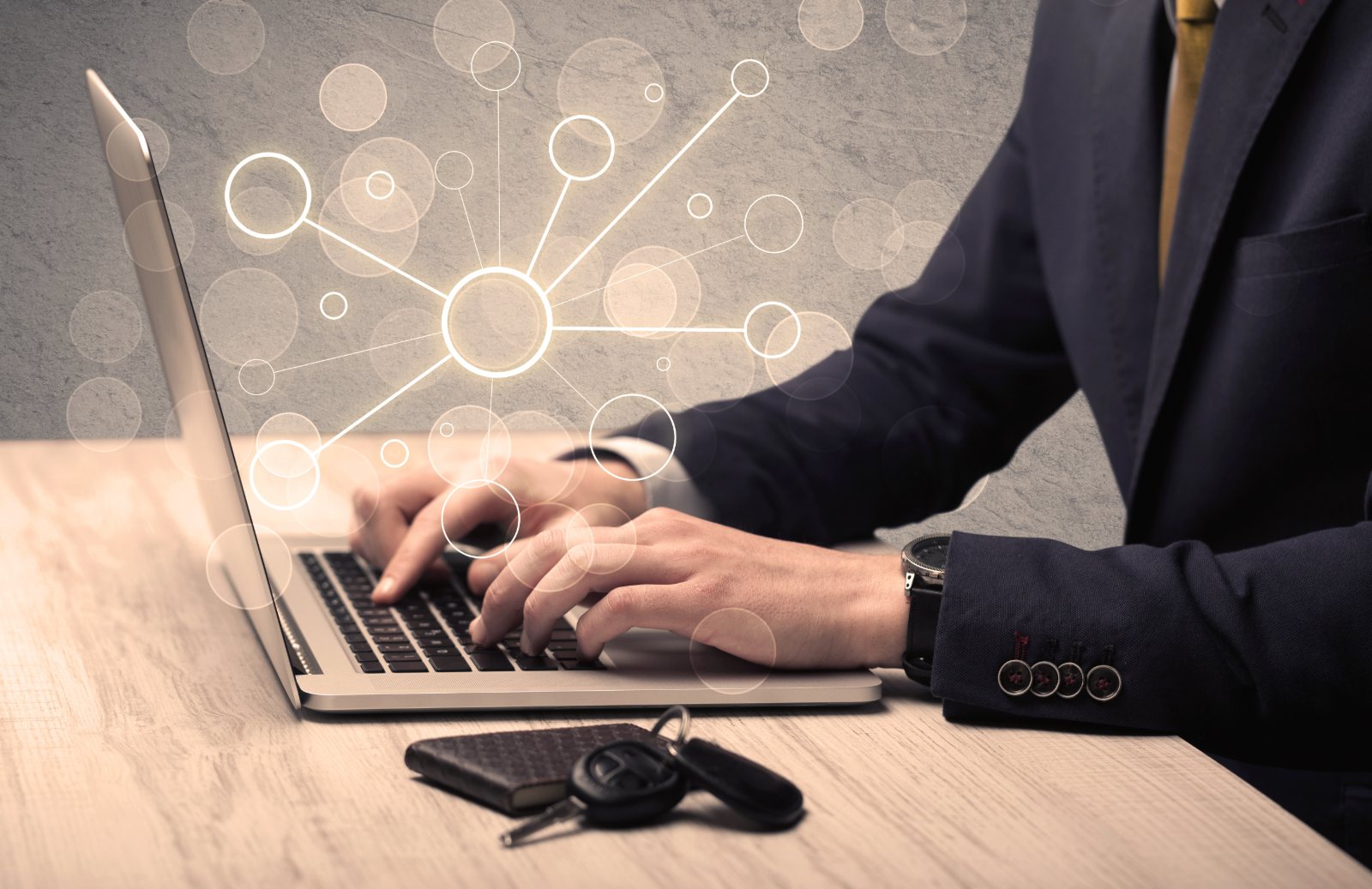 A businessman typing on a laptop with glowing network nodes rising from the keyboard