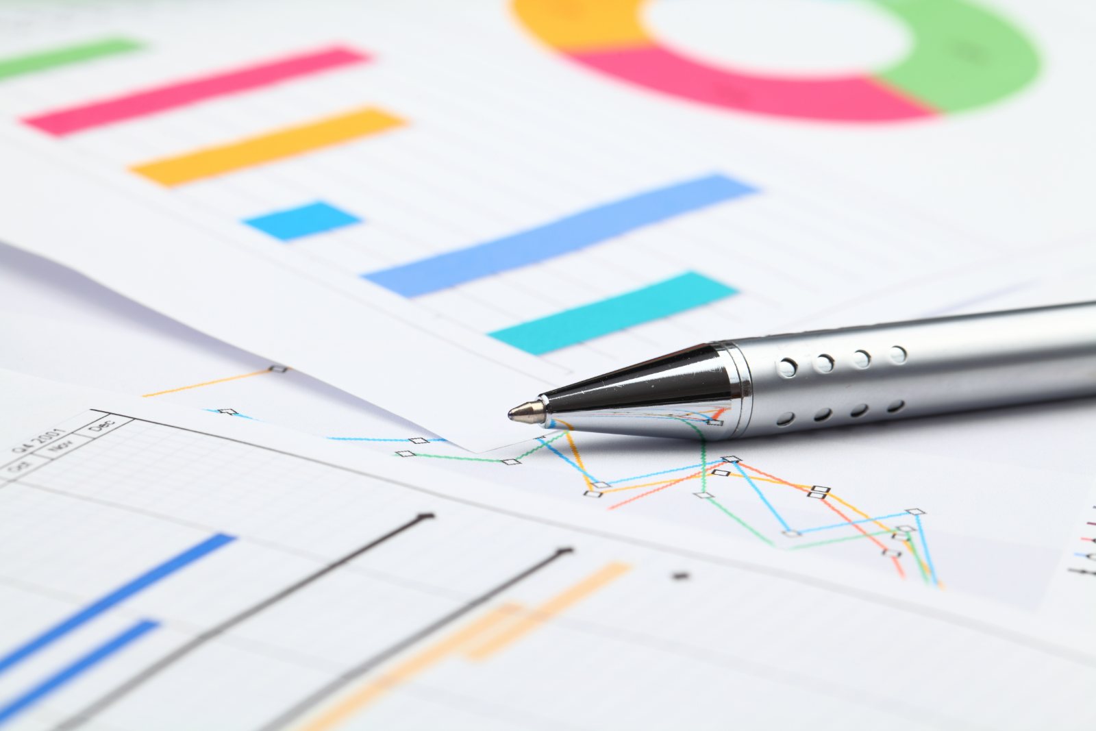 Colourful printed bar, line and donut charts with a silver pen